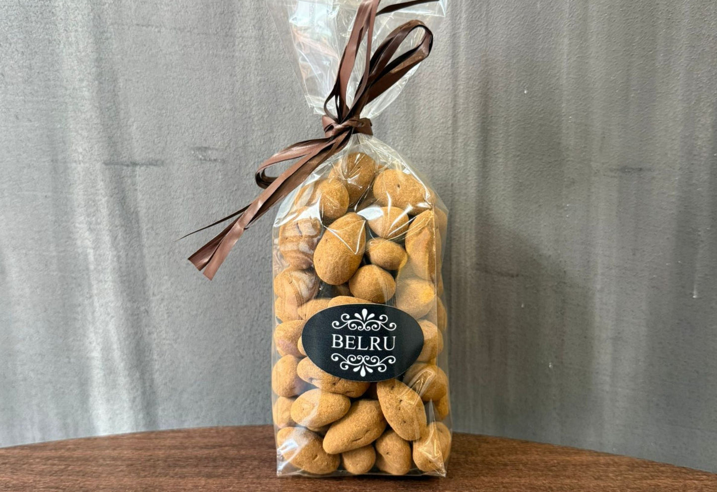 Bag of Belru cookies with a decorative ribbon on a wooden surface and gray background