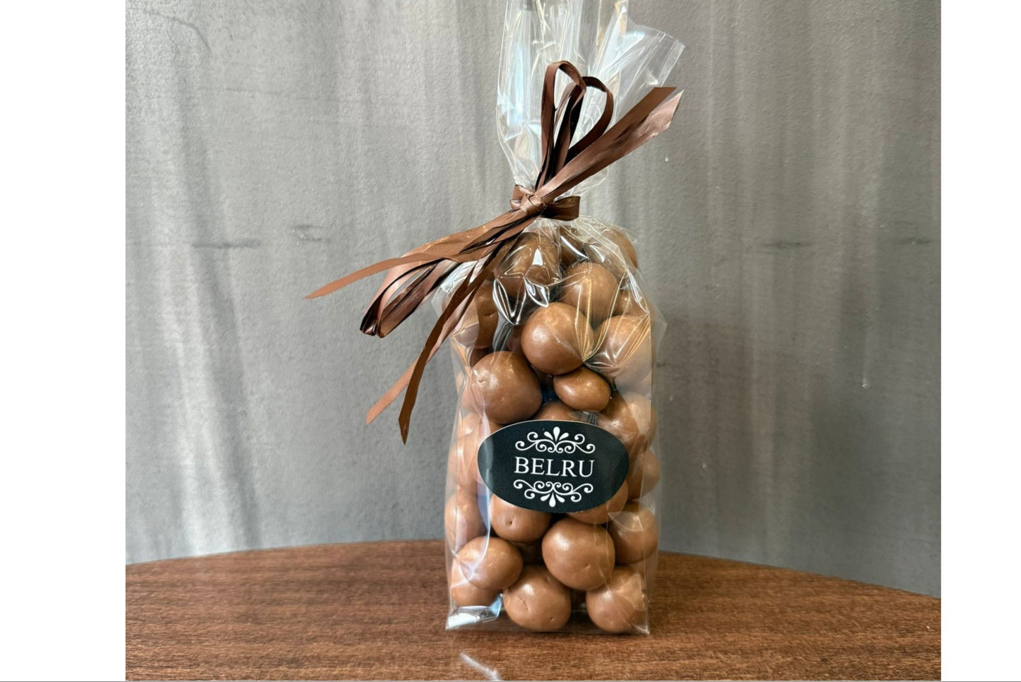 Bag of chocolates with a visible 'BELRU' label on a wooden surface and gray background