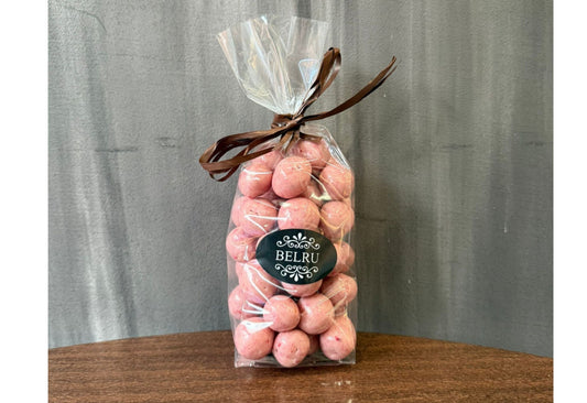 Bag of pink candies with a visible brand label on a wooden surface and gray background