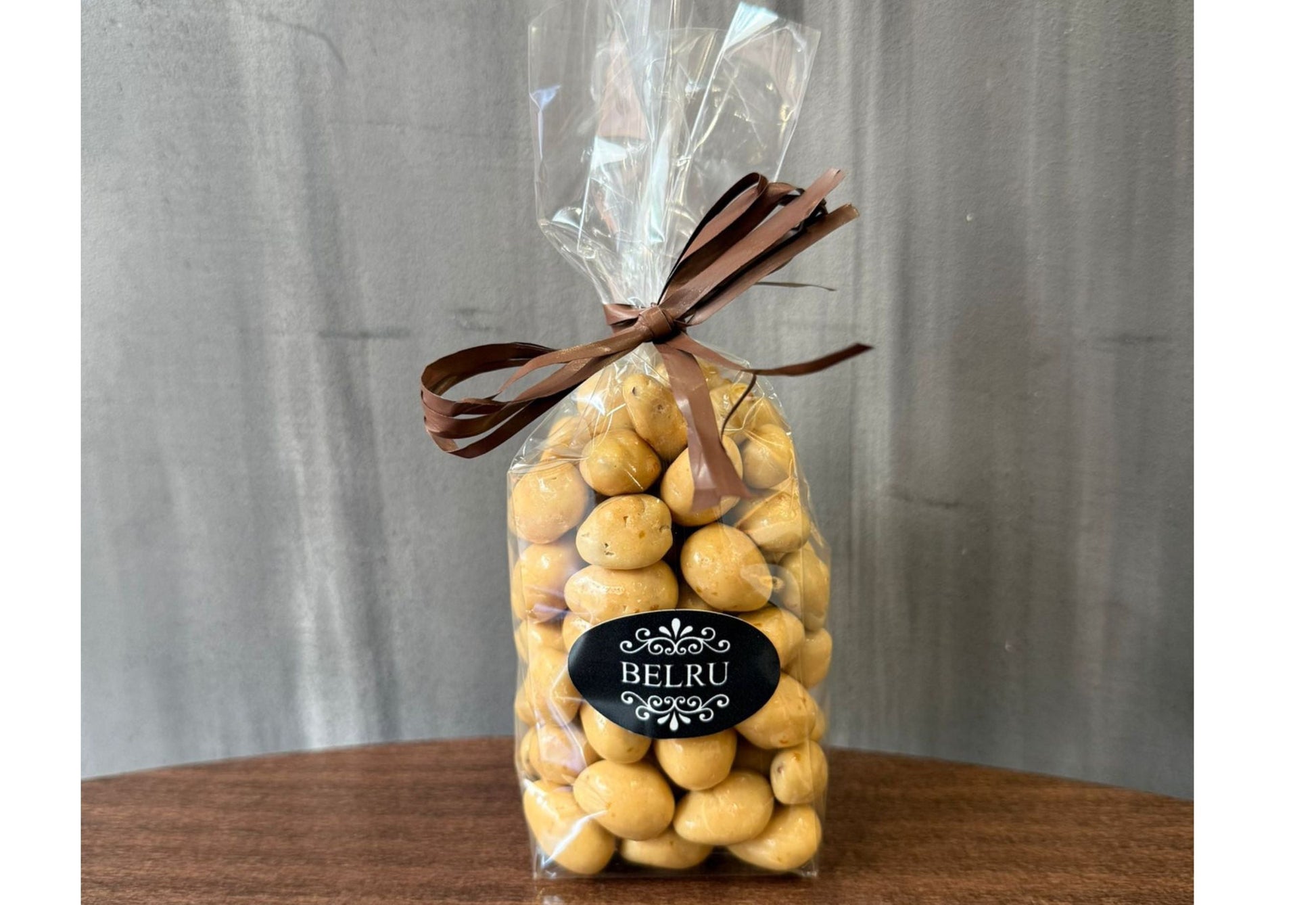 Bag of yellow candies with a brown bow and 'BELRU' label on a gray background